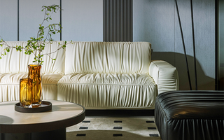 Cream leather sofa paired with black ottoman in modern living room.